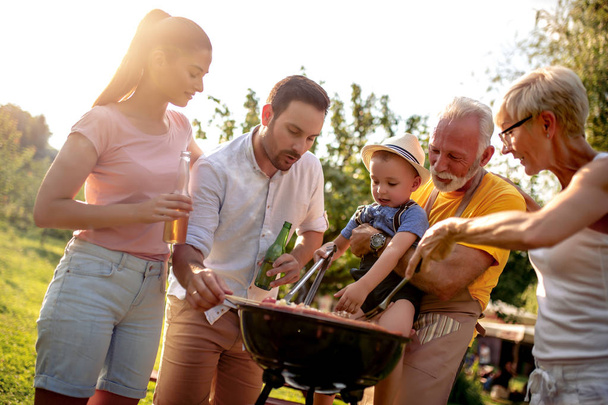 Boldog nagy család gyűlt össze a grill körül piknik.Szabadidő, élelmiszer, család és nyaralás koncepció. - Fotó, kép