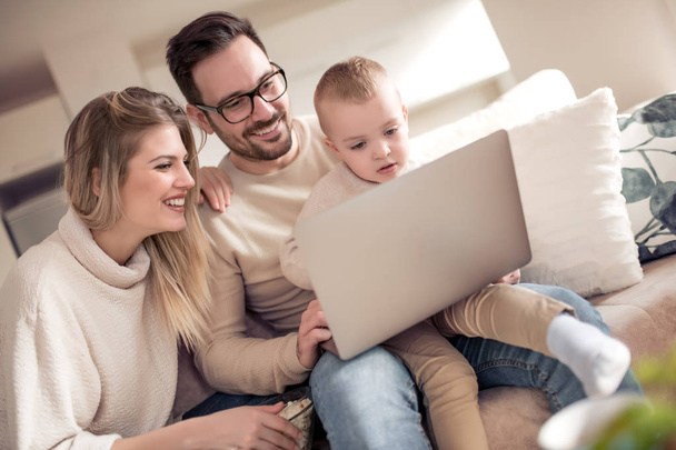 Parents heureux avec fils en utilisant un ordinateur portable dans le salon
. - Photo, image