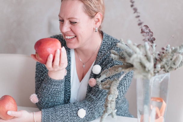 cheerful mid adult caucasian woman having fruits at kitchen - Fotoğraf, Görsel