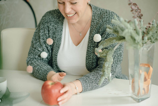 cheerful mid adult caucasian woman having apple at kitchen - 写真・画像