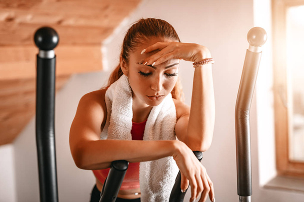 женщина измучена и взять перерыв от тяжелых упражнений в гостиной на дому
 - Фото, изображение