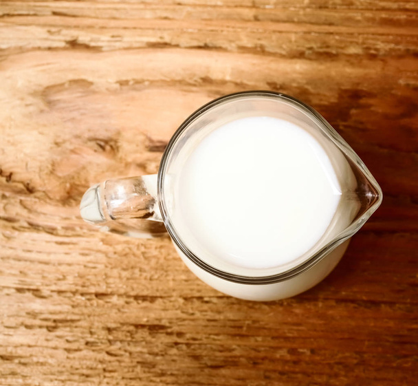 glass  jug of milk on a wooden background. top view  - Fotó, kép
