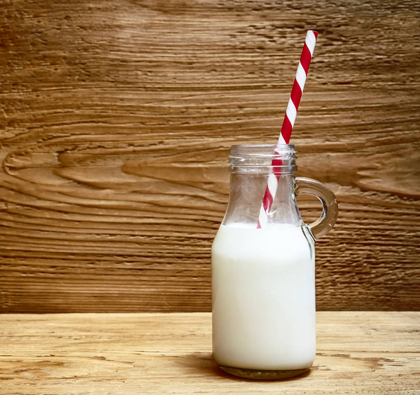 botella de leche con paja sobre fondo de mesa de madera
 - Foto, imagen