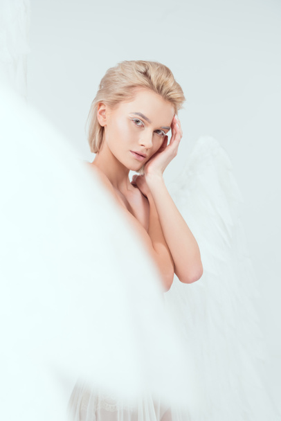 enfoque selectivo de la hermosa mujer con alas de ángel mirando a la cámara aislada en blanco
 - Foto, Imagen