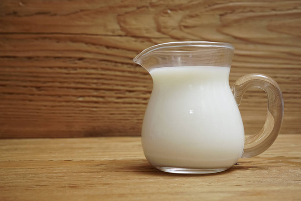 glass jug of milk on a wooden background - Φωτογραφία, εικόνα