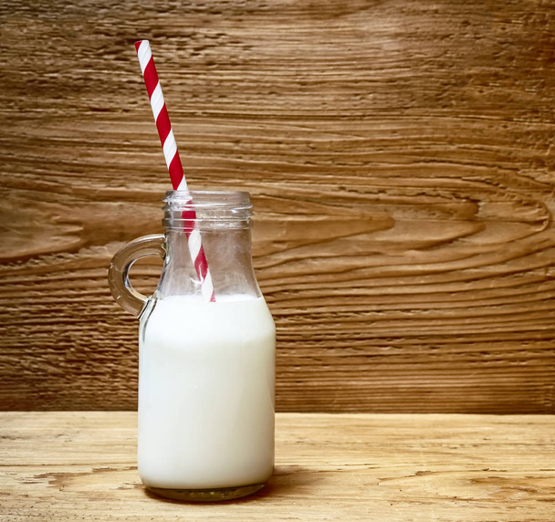 bottle of milk with straw on wooden table background - 写真・画像