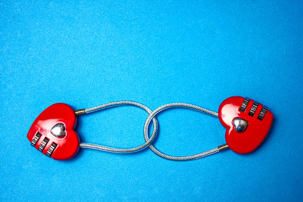 Two linked to each other padlocks in form of hearts isolated on blue   background. 14th February - happy Valentines day.  - 写真・画像