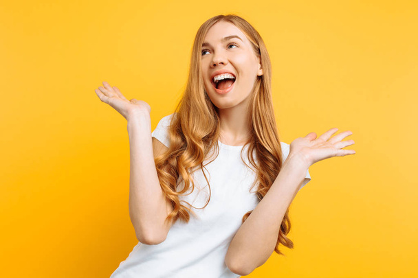 Happy young woman in white t-shirt posing on yellow background - Foto, imagen