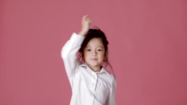 little child girl in white shirt dancing on pink background. - Metraje, vídeo