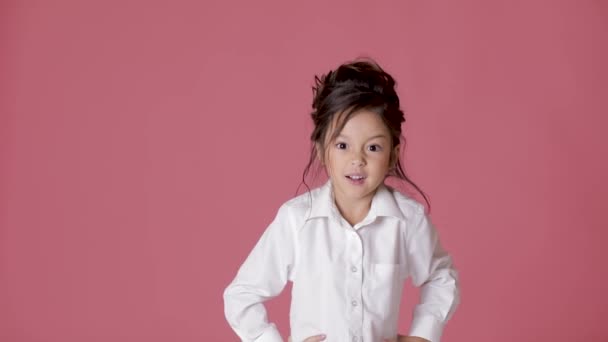 cute little child girl in white shirt shows different emotions on pink background. - Filmati, video