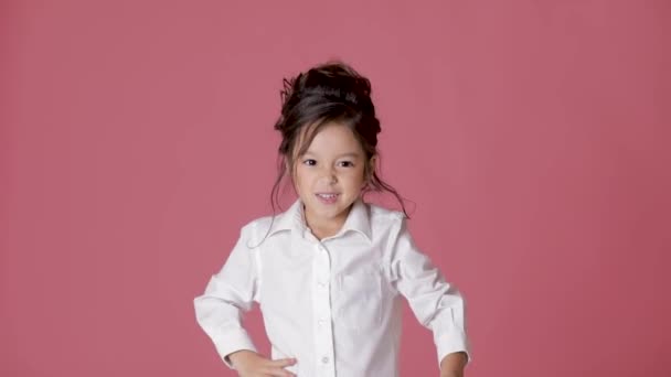 cute little girl in white shirt shows different emotions on pink background. lot of gestures and facial expressions of child - Footage, Video