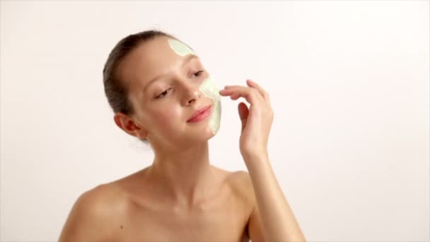 The Young Beautiful Girl Has Caused A Cosmetic Mask, White Face Cream Skin Health, Stands On A Light Background Prores Codec - Filmagem, Vídeo