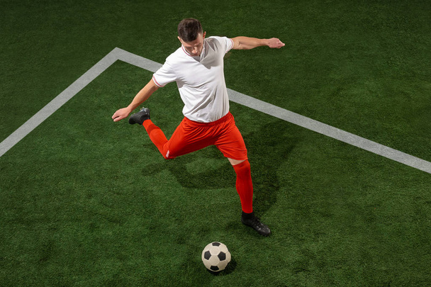 Football player tackling ball over green grass background - Photo, Image