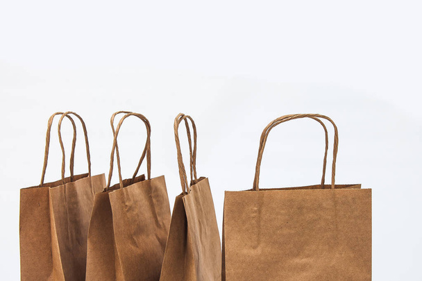 Kraft bolsas sobre un fondo blanco en una fila - venta, compras y regalos
 - Foto, Imagen