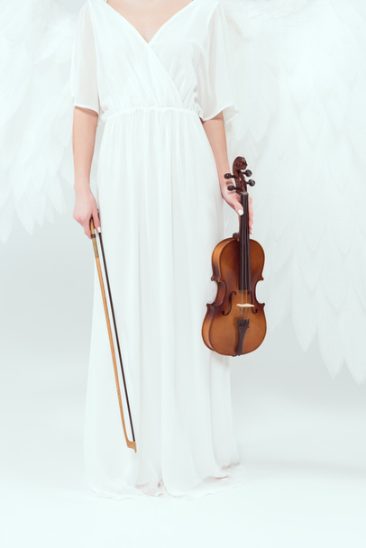 обрізаний вид жінки в костюмі ангела з крилами, що тримають скрипку і лук ізольовані на білому
 - Фото, зображення