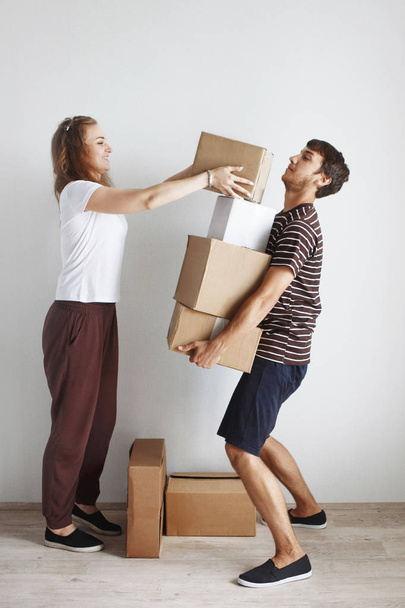 Young couple sitting on floor in new apartment after repair among cardboard boxes  - Foto, Bild