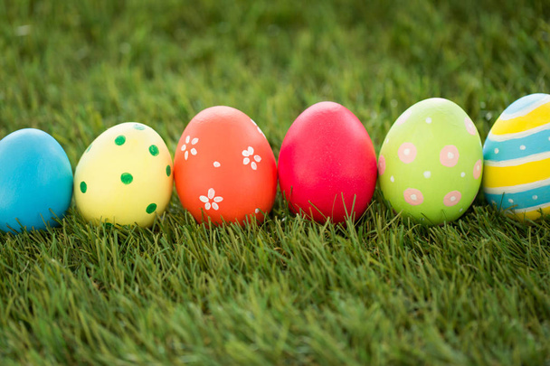 row of colored easter eggs on artificial grass - Zdjęcie, obraz