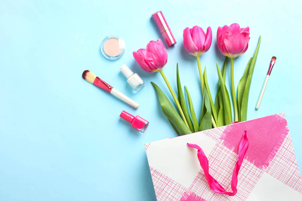Boeket van mooie roze tulpen in pakket en cosmetica op blauwe achtergrond. Concept internationale Vrouwendag, 8 maart. Bovenaanzicht, kopie ruimte, - Foto, afbeelding