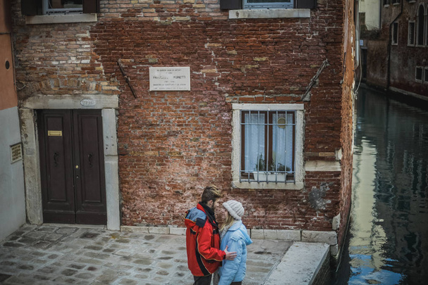 Verliebtes Paar umarmt sich in der Nähe des Kanals in einer engen Straße zwischen Häusern in der Altstadt, Venedig, Italien  - Foto, Bild