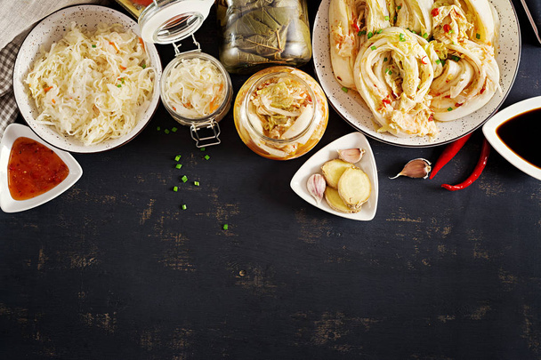 Που έχουν υποστεί ζύμωση τροφίμων. Χορτοφάγους τροφίμων έννοια. Λάχανο kimchi, μαριναρισμένο ντομάτες, λάχανο τουρσί ξινή γυάλινα βάζα πάνω από αγροτική κουζίνα πίνακα. Έννοια των κονσερβοποιημένων τροφίμων. Το top view. Επίπεδη θέσει - Φωτογραφία, εικόνα