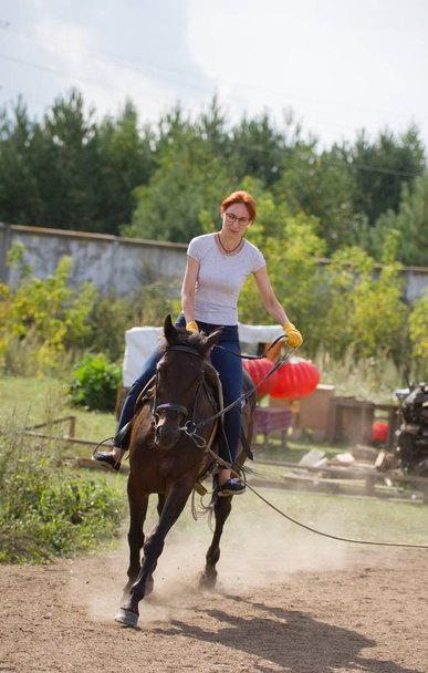 A redhead woman riding a horse in nature - Φωτογραφία, εικόνα