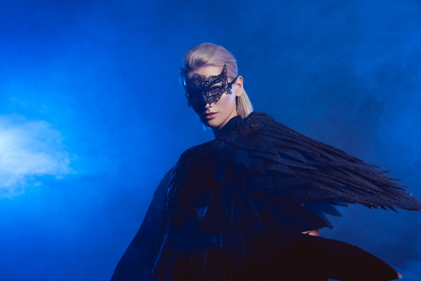 belle femme mystérieuse avec masque en dentelle et ailes d'ange noir sur fond bleu foncé avec espace de copie
 - Photo, image