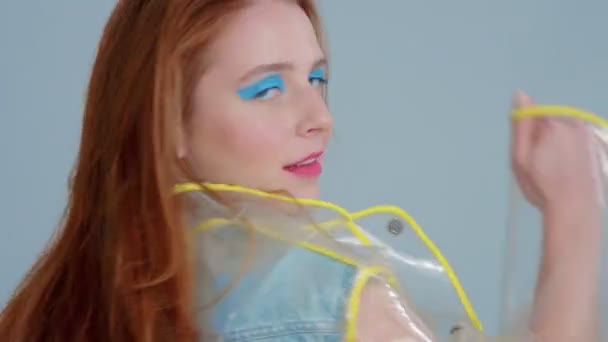 zrzavé vlasy žena v transparentní pláštěnka s pop art světlý make-up tanec - Záběry, video