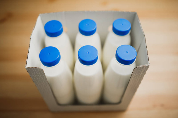 butelek mleka w kartonie na drewnianym stole - Zdjęcie, obraz