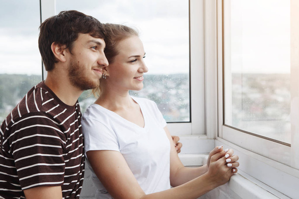 linda pareja mirando por la ventana en un nuevo hogar
 - Foto, imagen