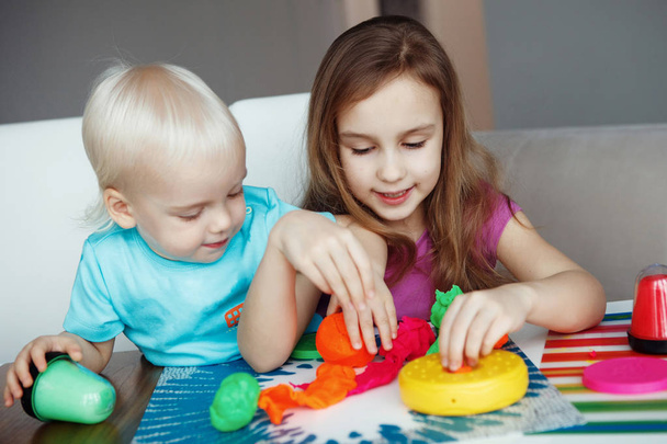oğlan ve kız evde masada oturan hamuru ile oynamaktan - Fotoğraf, Görsel