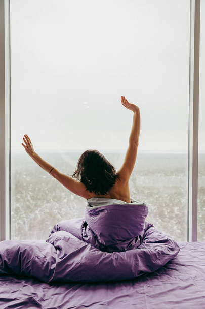 young brunette woman waking up next to the window  - Φωτογραφία, εικόνα