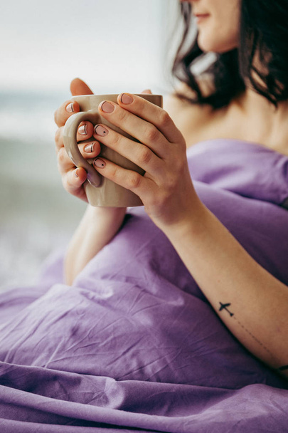 jonge brunette vrouw het drinken van thee in de ochtend zittend in de buurt van het venster  - Foto, afbeelding