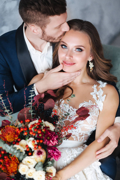 Wedding couple with bride holding bouquet. Sensual portrait of a young couple. Wedding photo indoor - Foto, imagen