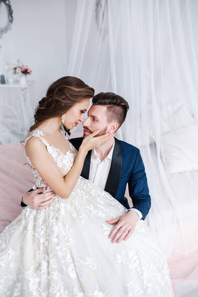 Wedding couple hugging each other indoor. Beautiful model girl in white dress. Man in suit. Beauty bride with groom. - Fotografie, Obrázek