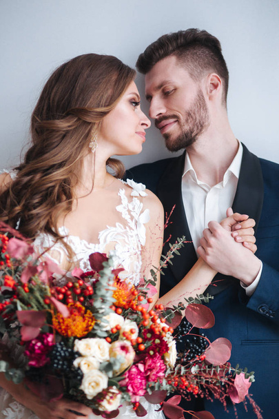 Wedding couple with bride holding bouquet. Sensual portrait of a young couple. Wedding photo indoor - Foto, Bild