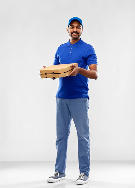 happy indian delivery man with pizza boxes in blue - Foto, afbeelding
