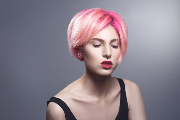 Portrait of young woman with pink hair on gray background - Photo, Image