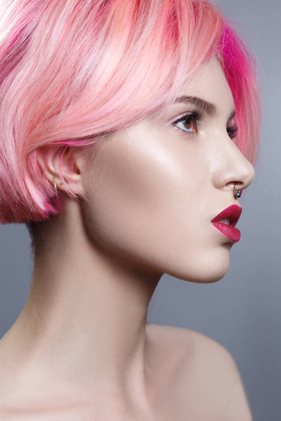 Portrait of young woman with pink hair on gray background - 写真・画像