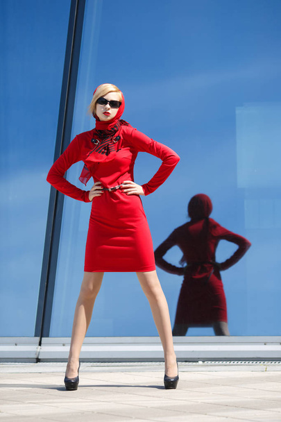 Portrait of young woman in red dress against glass wall - Foto, Imagem
