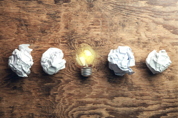 Crumpled papers with light bulb on wooden background. Idea - Photo, Image
