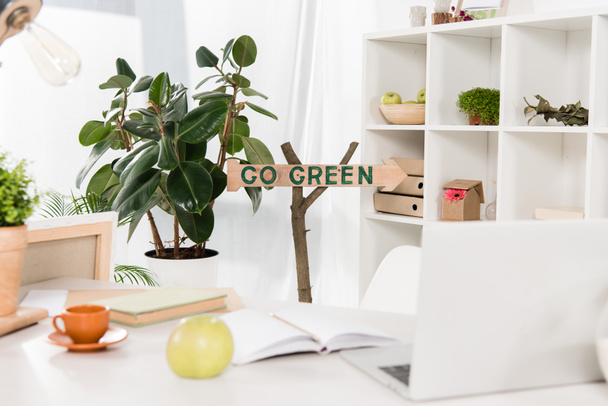 spazio di lavoro con mela e laptop vicino andare segno verde in ufficio moderno, concetto di risparmio ambientale
  - Foto, immagini