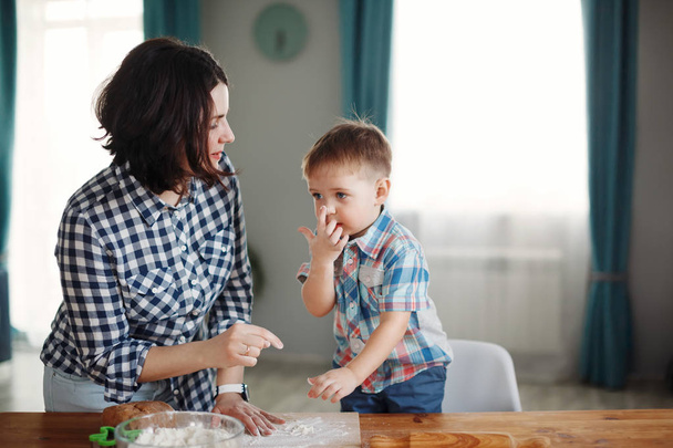 Mother and son dressed in plaid shirts cooking in kitchen of flour and dough - Foto, immagini