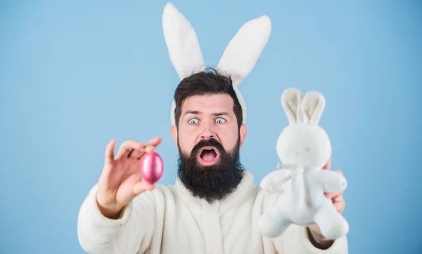 Bearded man wear bunny ears. Egg hunt. Look what i found. Hipster cute bunny blue background. Easter bunny. My precious. Funny bunny with beard and mustache hold pink egg. Easter symbol concept - Photo, image
