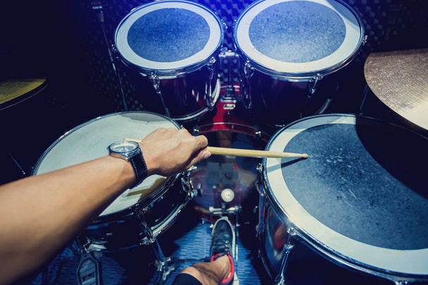 man spelen de drum set met houten drumsticks in muziekkamer, het concept van muziekinstrument - Foto, afbeelding