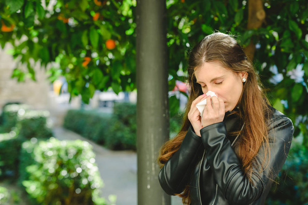 Donna dai capelli castani che usa un tessuto per soffiarsi il naso e pulirsi il naso da un raffreddore
. - Foto, immagini