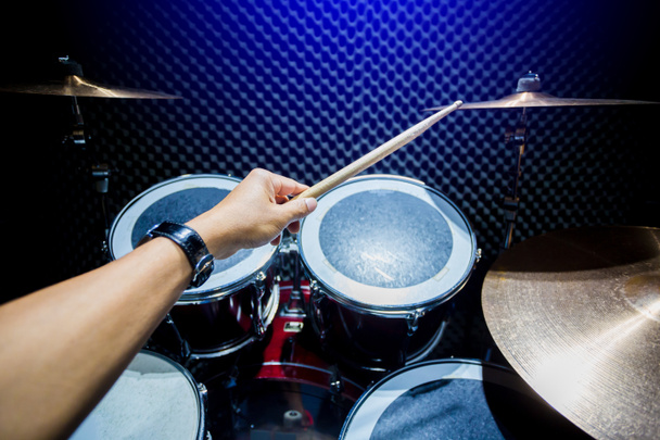 man playing the drum set with wooden drumsticks in music room , the concept of musical instrument - Photo, Image