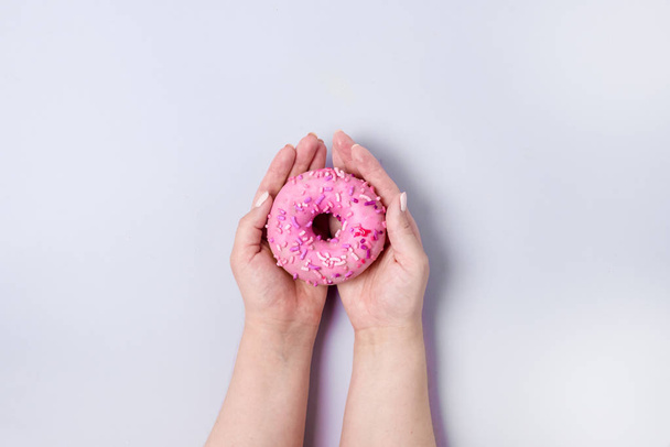 Female Hands Holding Sweet Donut with Sprinkles Blue Background Tasty Donut Top View - Fotó, kép