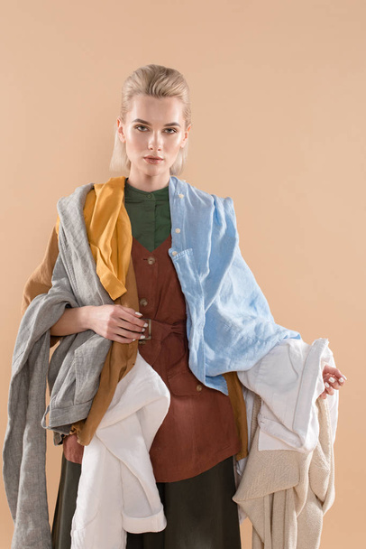 mujer atractiva sosteniendo ropa ecológica aislada en beige, concepto de ahorro ambiental
 - Foto, imagen