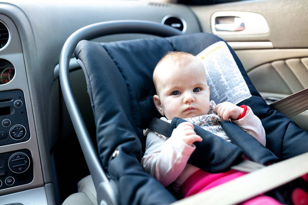 Ensuring safety of a little baby with infant car seat securely attached with a seatbelt - Fotó, kép