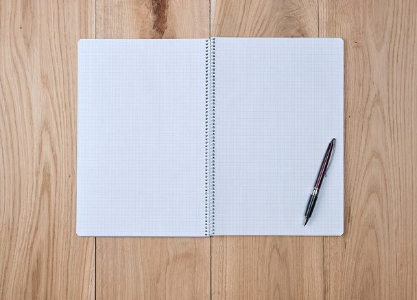 open notebook in a cell and a black wooden pen on a wooden background - Photo, image